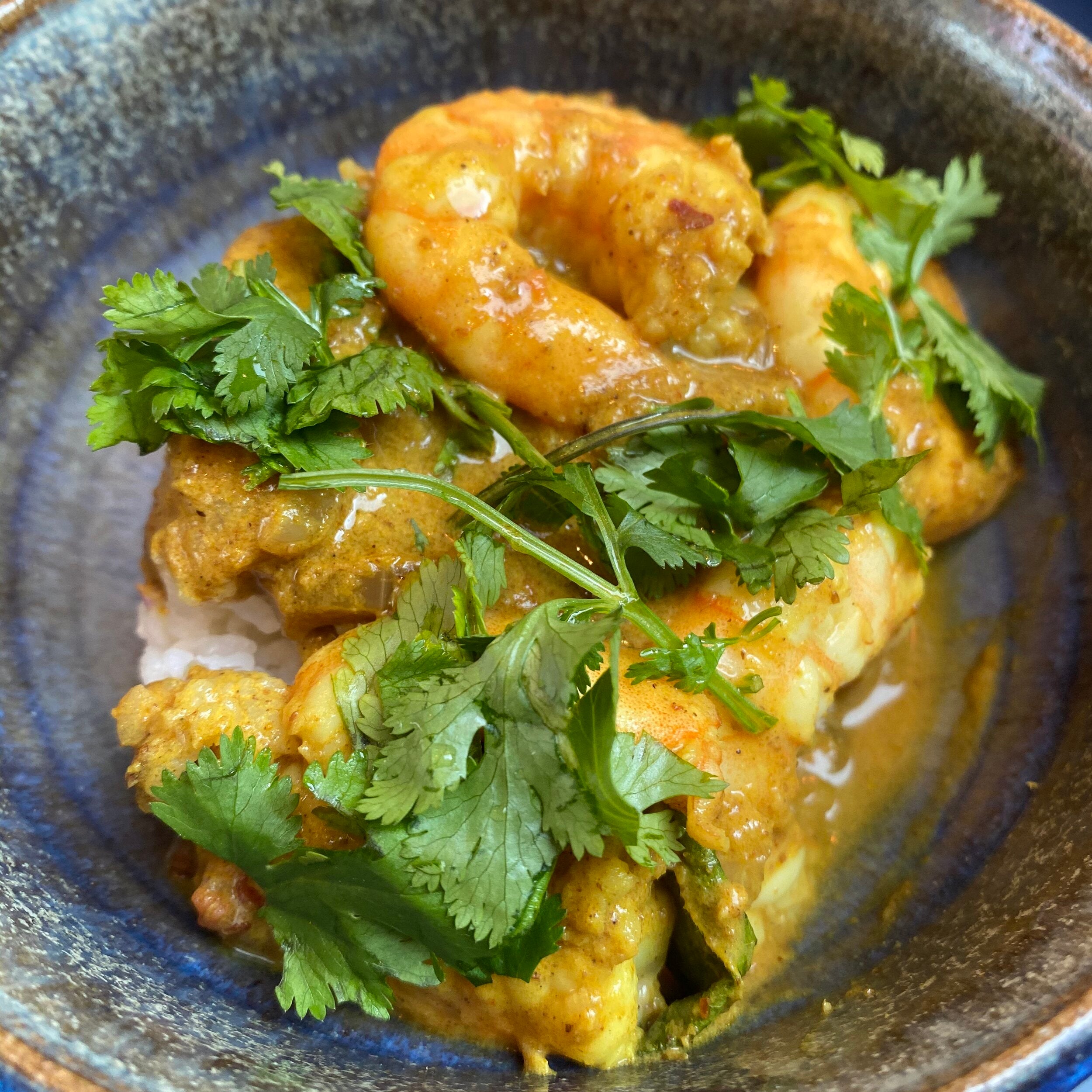 A plate of prawn curry garnished with coriander leaves.