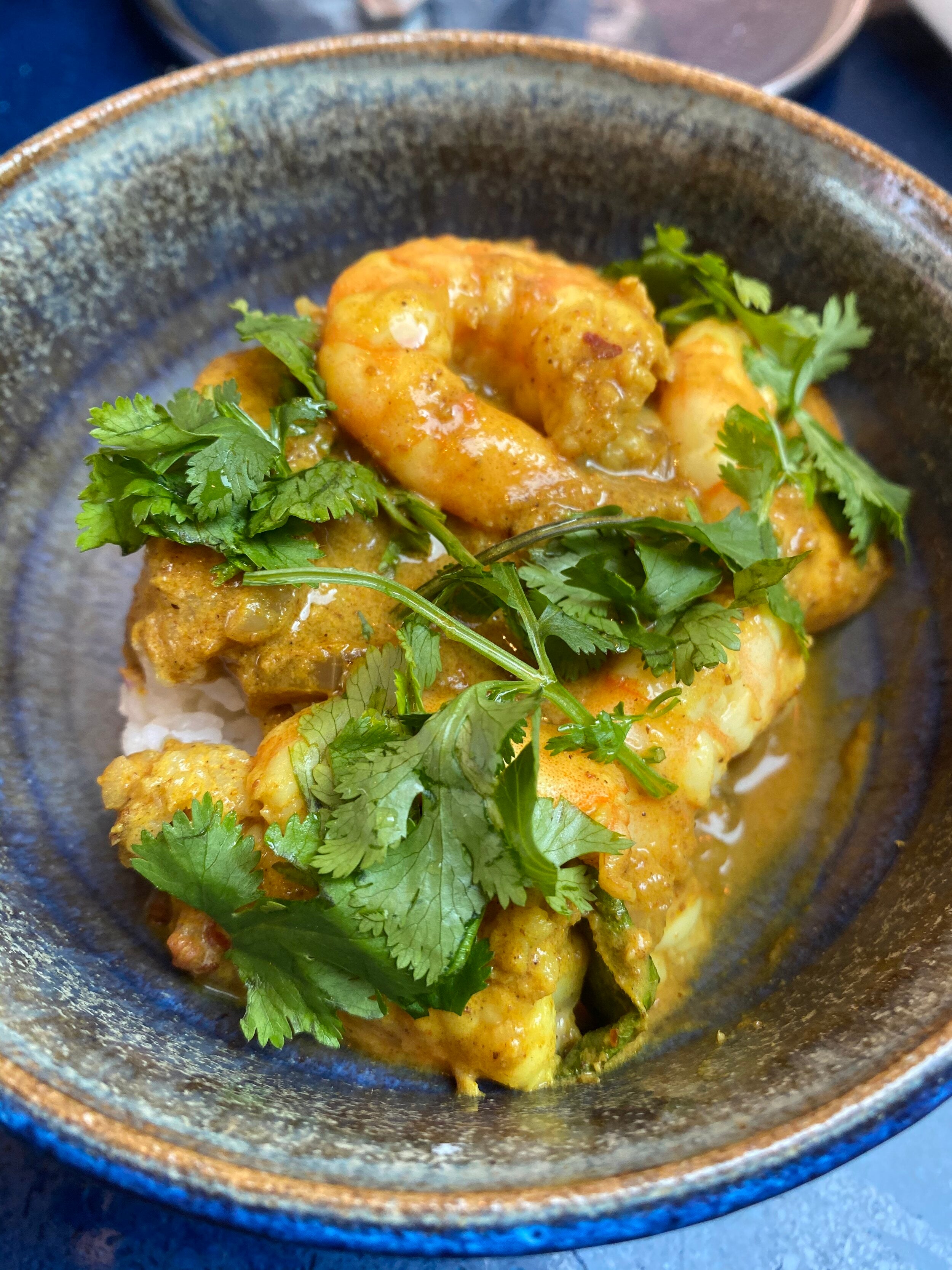 A plate of prawn curry garnished with coriander leaves.