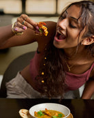 Lifestyle photo pf someone eating the prawn curry with a coconut roti while drops fall off the mouthful. 