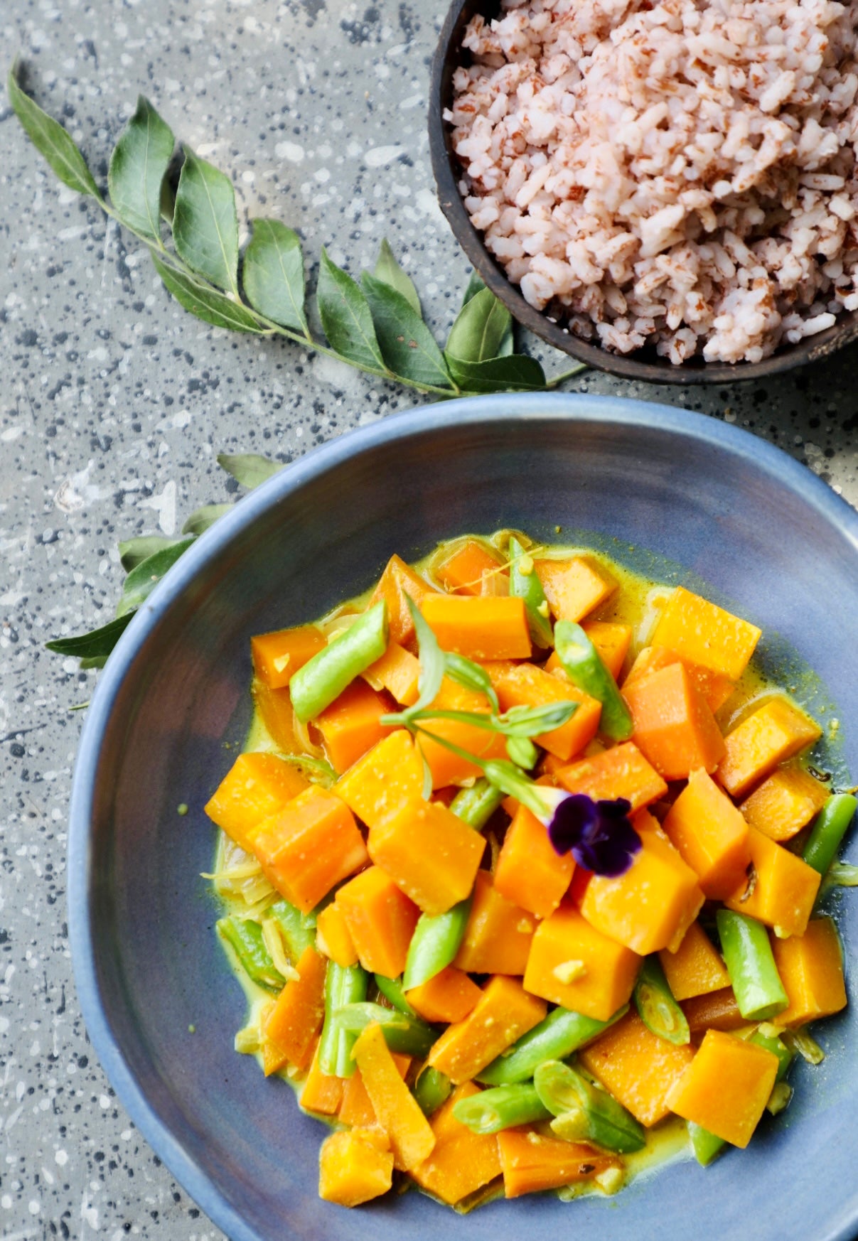 Blue bowl with yellow vegetable dish on a gray surface
