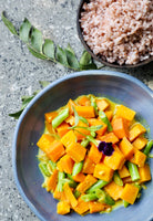 Blue bowl with yellow vegetable dish on a gray surface